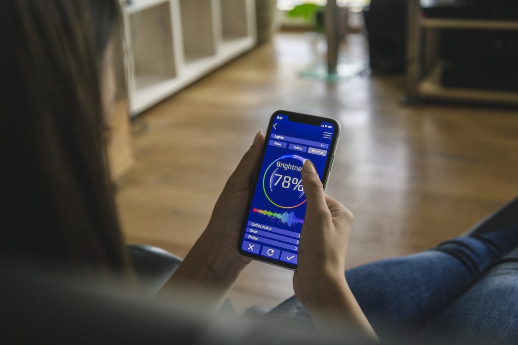 Young woman with smartphone with smart home control functions